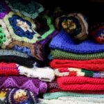 A stack of crochet blankets in different sizes and colours