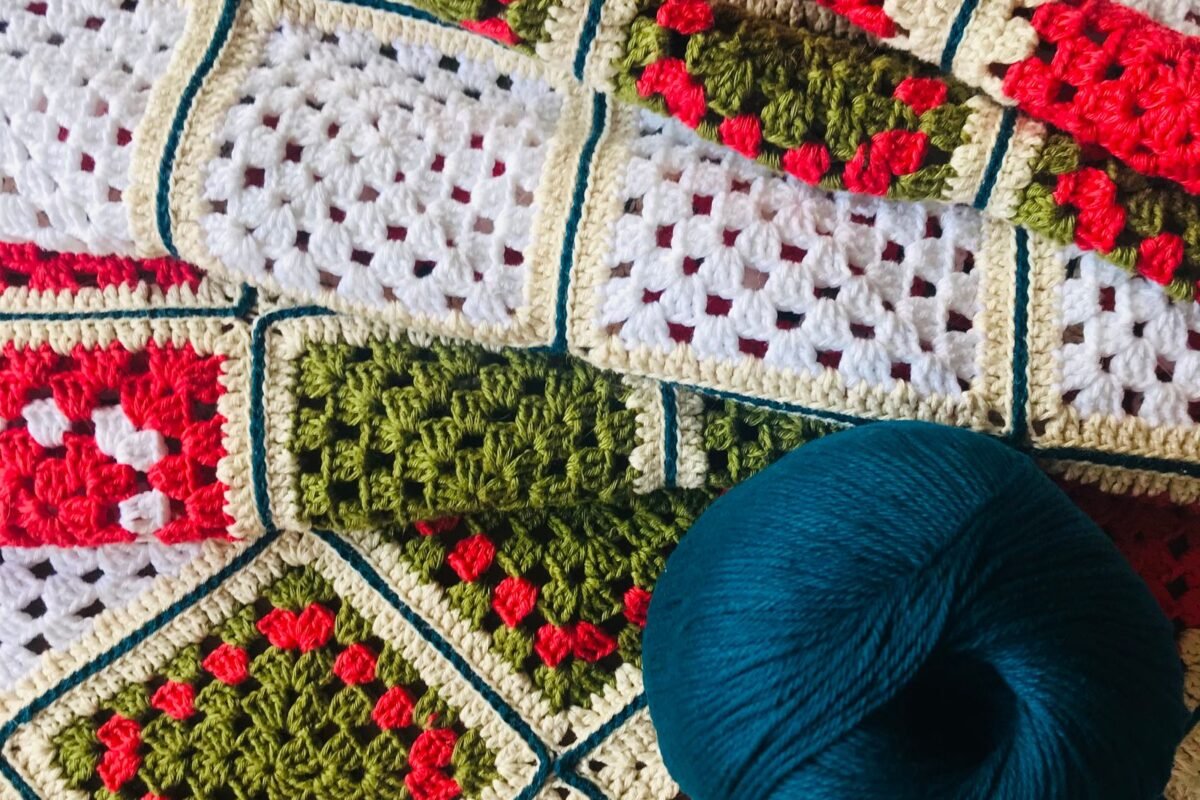 A ball of blue yarn resting on a finished crochet blanket