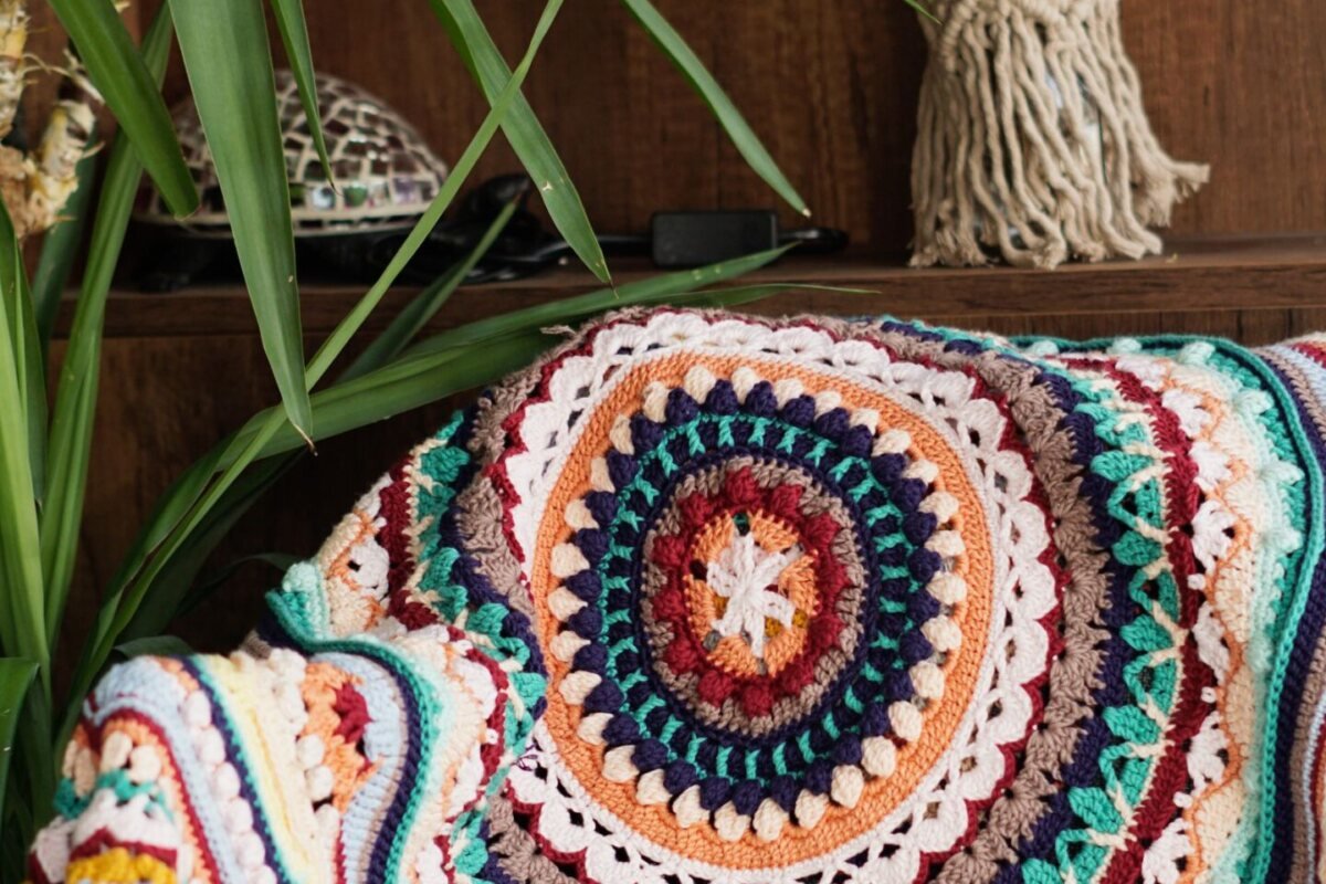 A crochet blanket worked in concentric rounds outward from a centre motif, draped over a chair