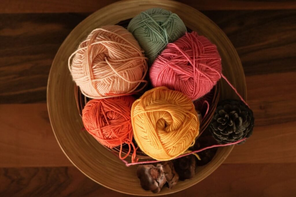 Yarn skeins in red green and gold with a pine cone, the colours a christmas crochet blanket needs