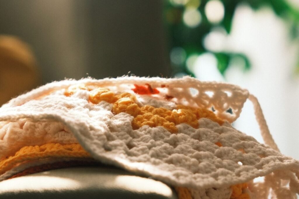 A folded fall crochet blanket in cream and warm orange with the stitch texture visible