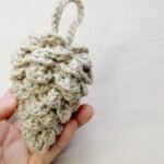 finished crochet pinecone from a free crochet pinecone pattern, held in one hand with a hanging loop