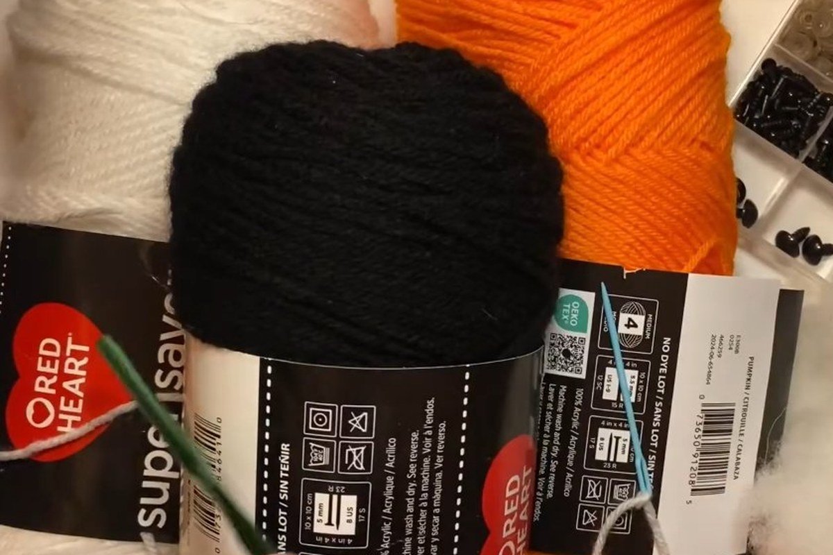 materials for a free crochet snowman pattern: white, black and orange Red Heart yarn, safety eyes and stuffing