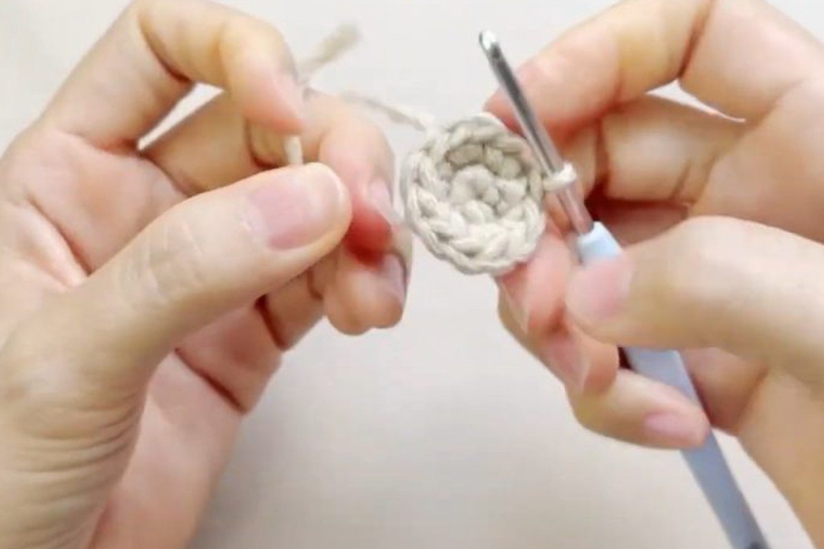 flat disc with a stitch marker at the start of round 3 of a free crochet pinecone pattern