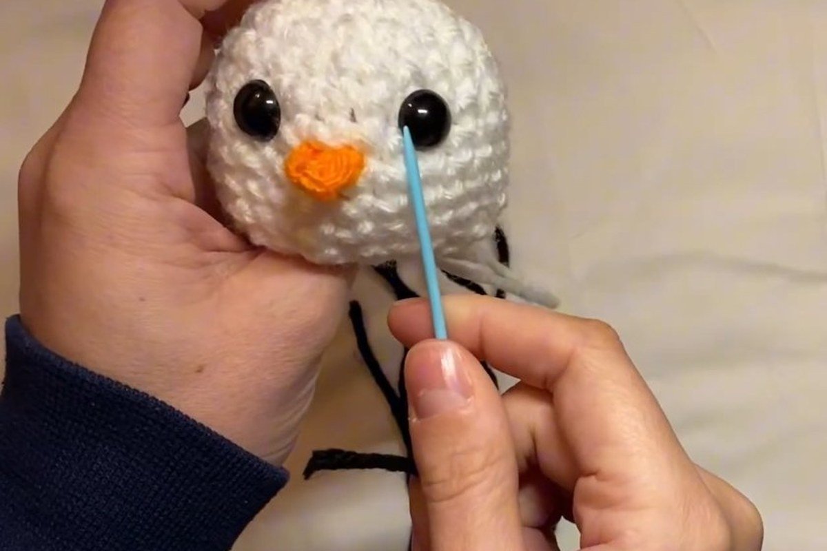 safety eyes and nose on the head of a free crochet snowman pattern