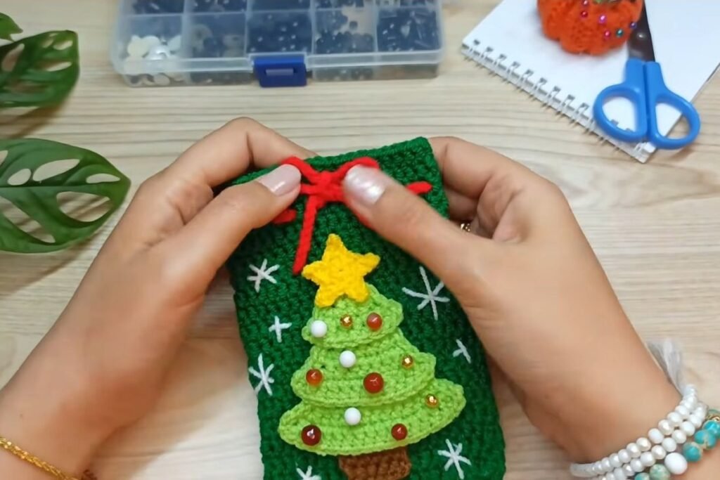 Finished crochet christmas tree gift bag with snowflakes, bead ornaments and a red bow