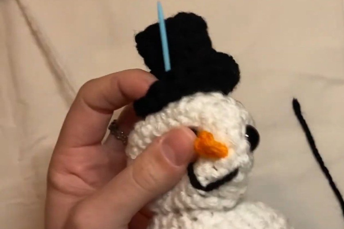 sewing the top hat onto the head of a free crochet snowman pattern