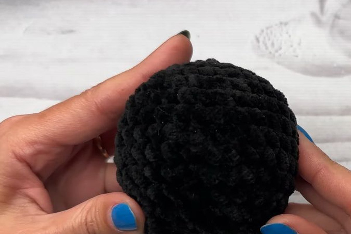 black crochet bat body with two small bobble feet at the bottom