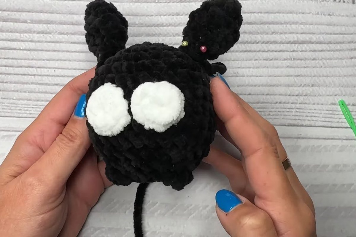 crochet bat with two white eyes sewn on before the pupils