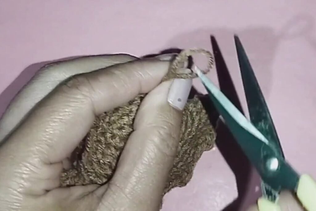 cutting the yarn tail on a finished crochet bat keychain
