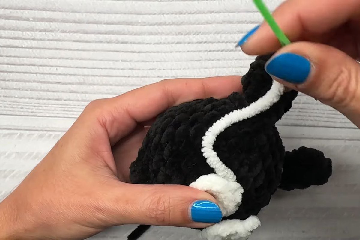 sewing a white eye onto a black crochet bat body with a yarn needle