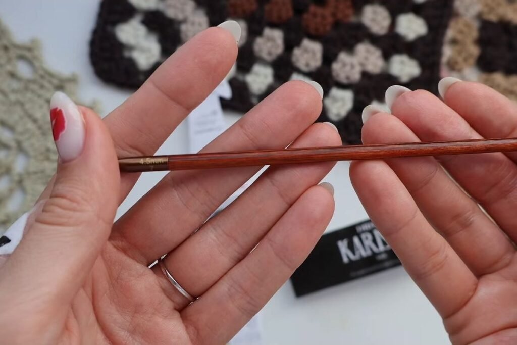 4.5 mm wooden crochet hook and wool yarn label in front of finished granny squares