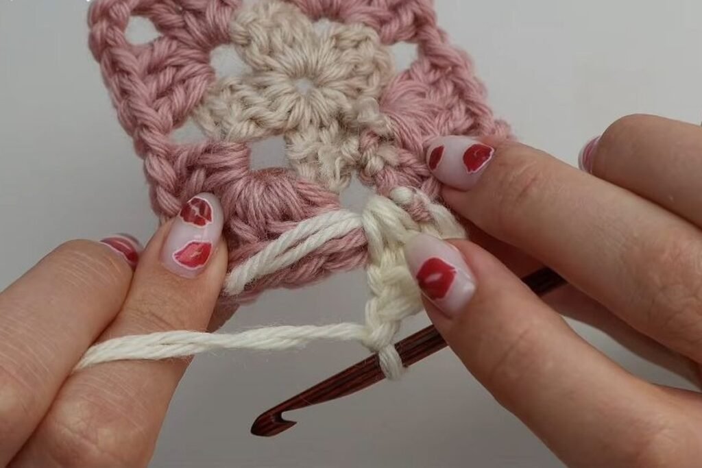round 3 of the granny square worked in cream yarn around a pink round