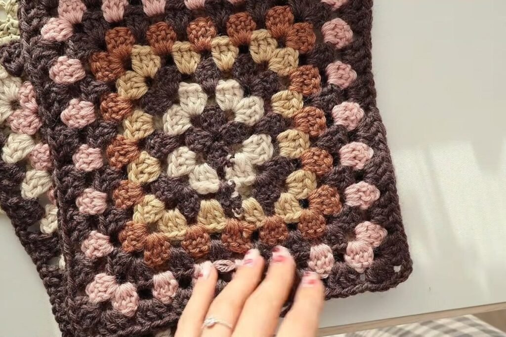 blocked granny squares for the crochet granny square cardigan stacked on a table