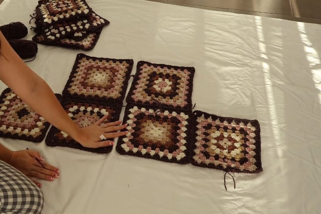 granny squares laid out on a bed in the shape of the cardigan before joining