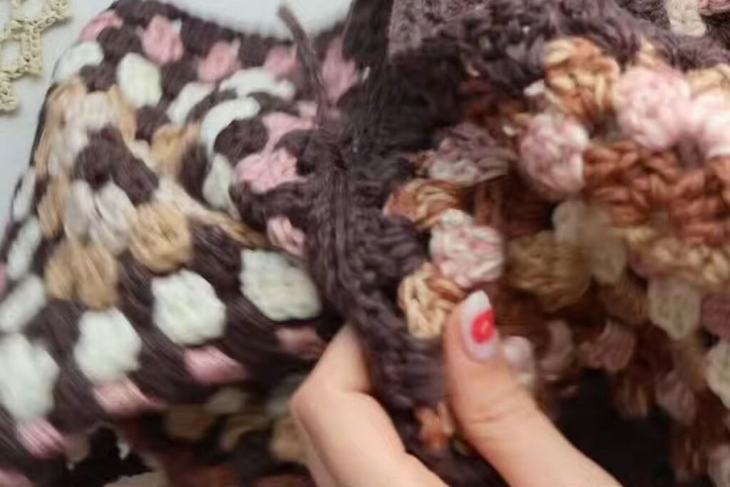 closing the sleeve seam of the granny square cardigan with slip stitches