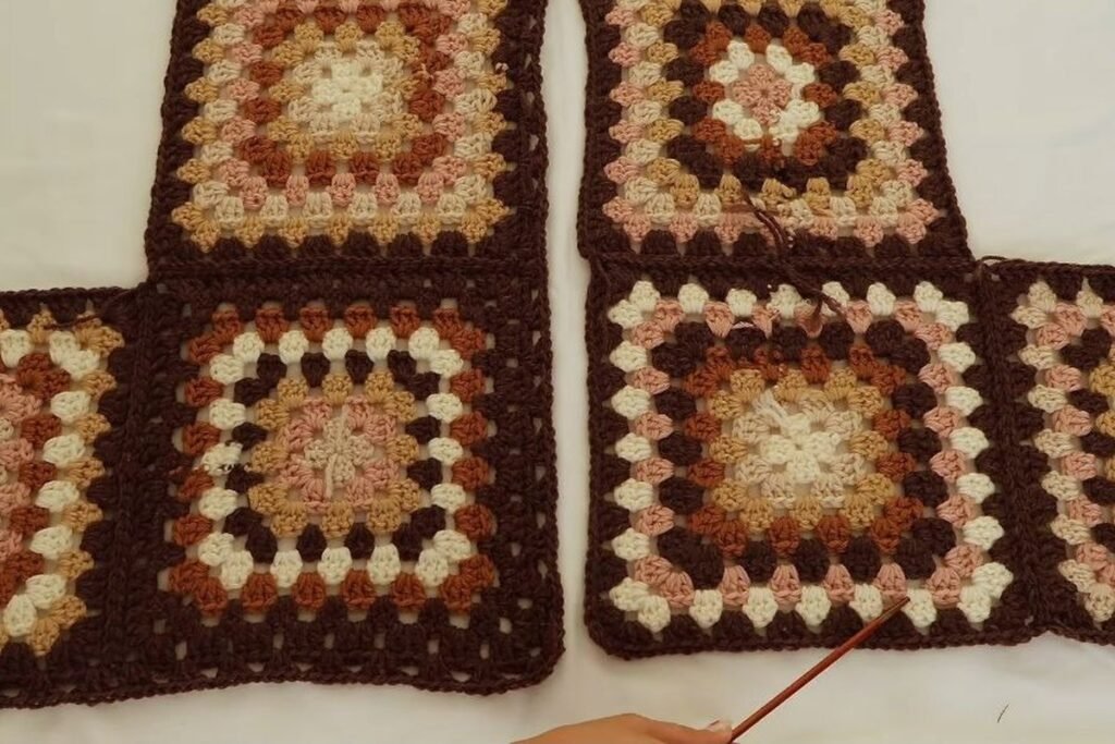 crochet granny square cardigan pieces laid flat: back and front granny squares in brown, pink and cream