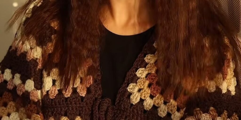 the finished crochet granny square cardigan worn over a black top