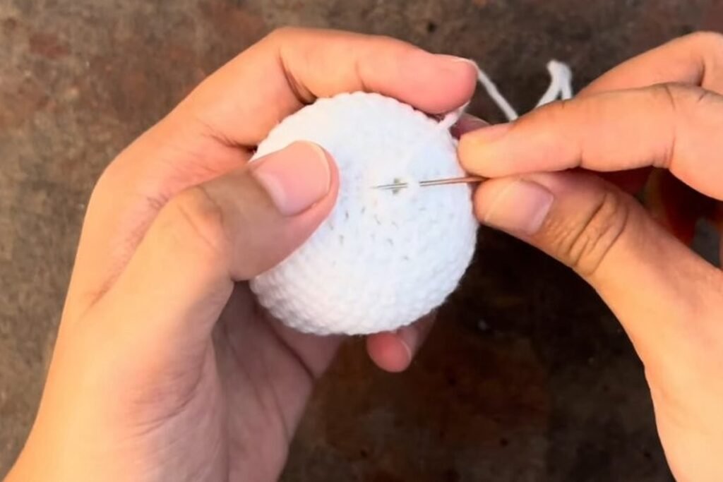 sewing the last 6 stitches of the crochet owl body closed with a yarn needle