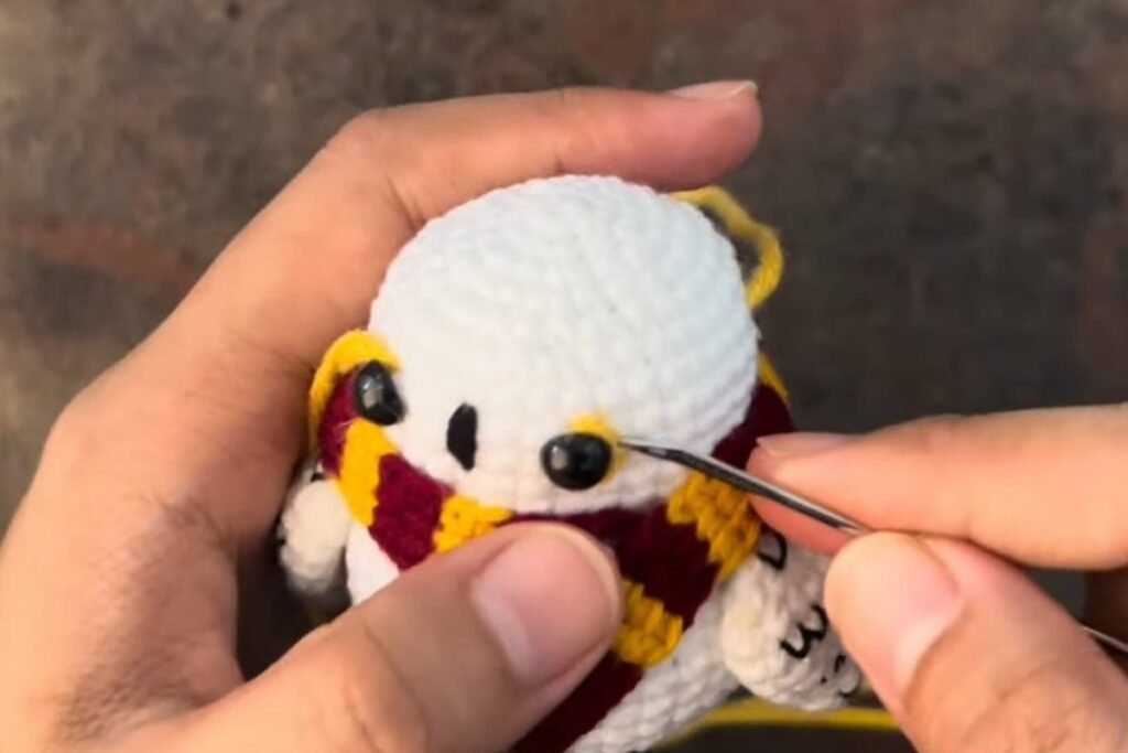 embroidering yellow rings around the eyes of a crochet snowy owl
