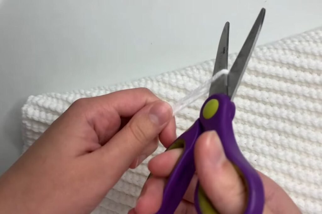 Cutting the yarn to fasten off the finished crochet scarf