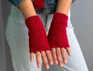 red crochet fingerless gloves worn on both hands, made from a free crochet fingerless gloves pattern