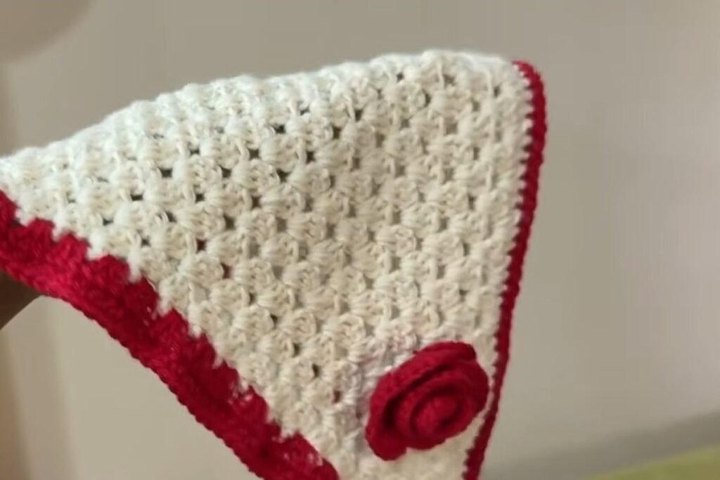 Finished free crochet head scarf pattern held up to show the rose and red border