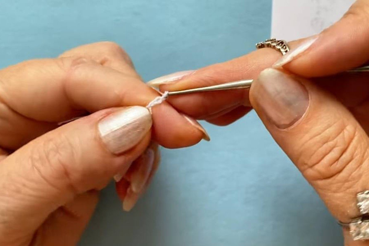 hands starting the centre ring of a free crochet snowflake pattern with a 1.0 mm hook