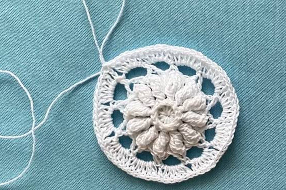 round crochet snowflake disc after round 6 with a lacy edge