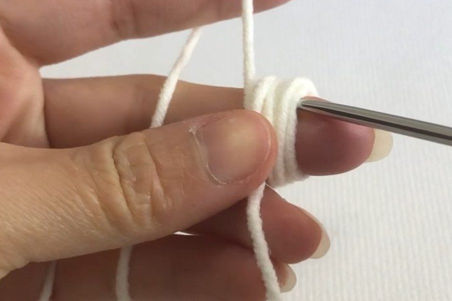 crochet hook inserted into the wrapped loops at the start of a puff stitch crochet snowflake