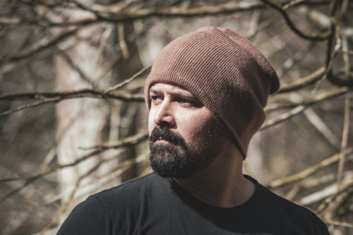 A bearded man outdoors wearing a close fitting ribbed beanie