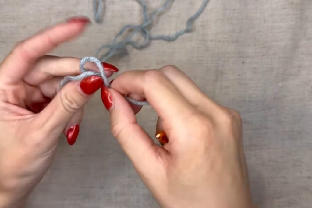 making a slip knot in blue yarn to start a crochet scarf