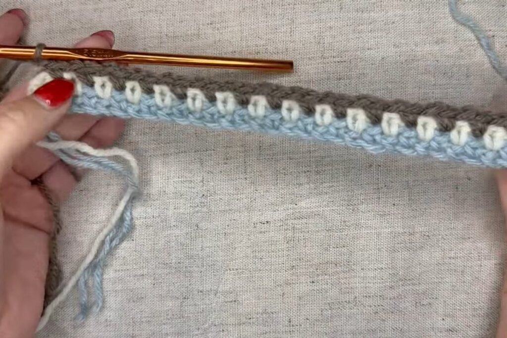 three colour stripes forming in a moss stitch crochet scarf
