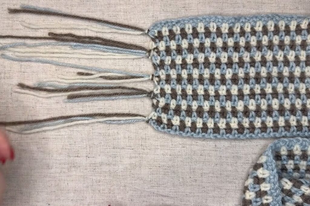 finished knotted tassels on the end of a moss stitch crochet scarf