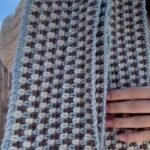 moss stitch crochet scarf in blue, cream and taupe stripes worn over a cream sweater