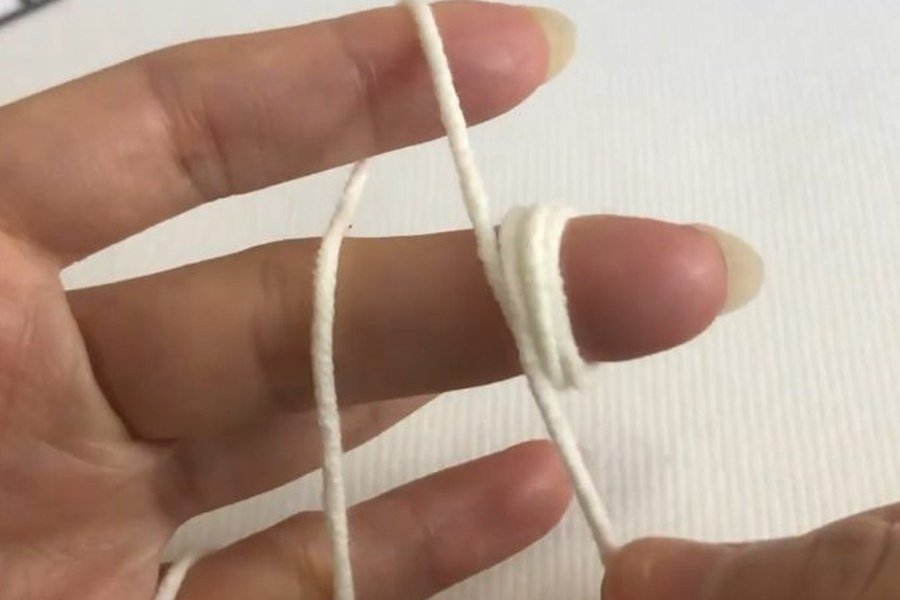 nine loops of yarn wrapped around a middle finger to start a puff stitch crochet snowflake