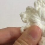 finished white puff stitch crochet snowflake held in a hand showing six puffs around the centre hole