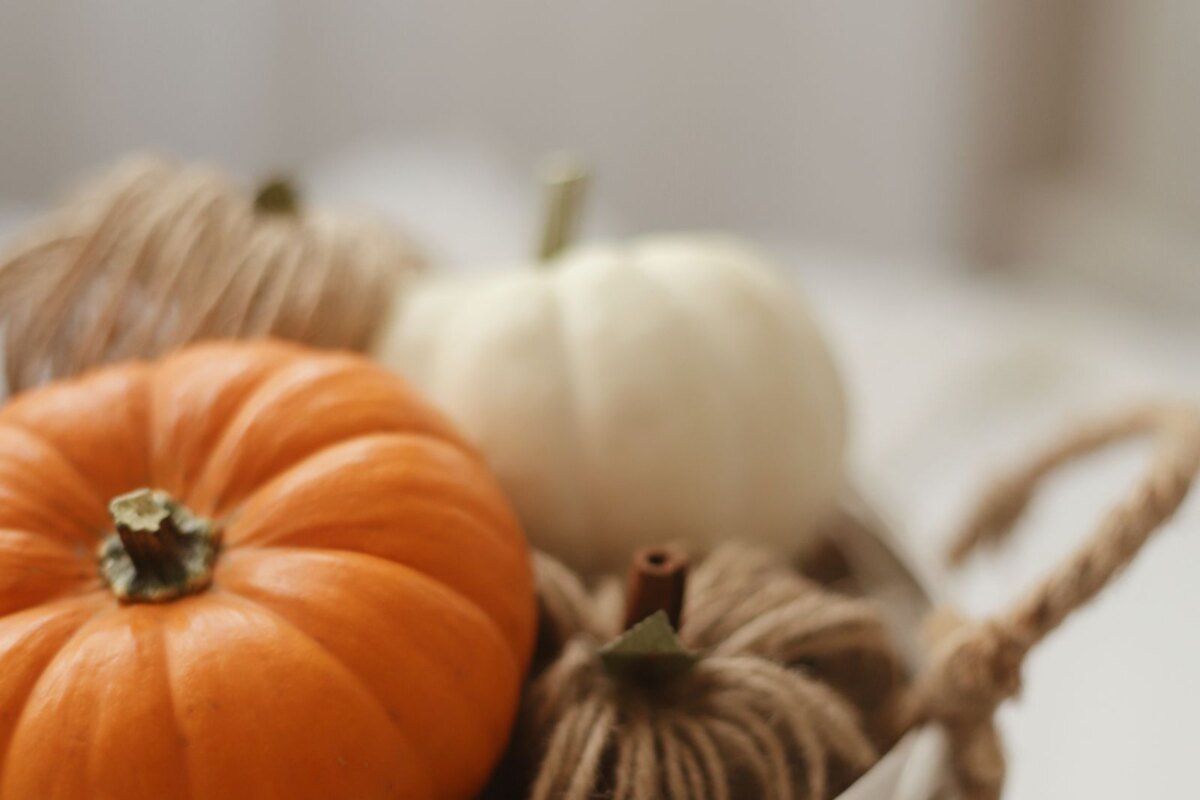 Small pumpkins and a ball of wool in a woven basket, the autumn palette a pumpkin granny square suits