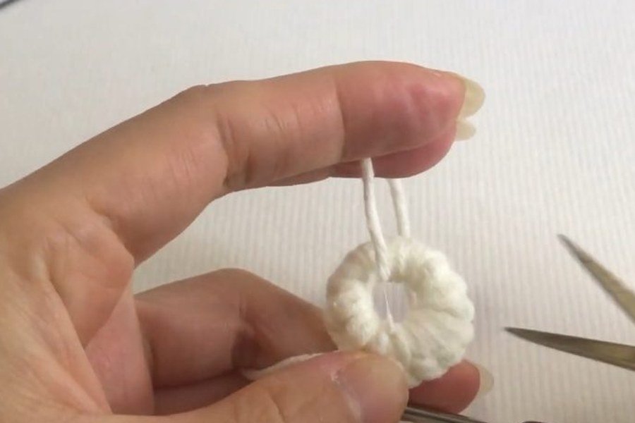 snipping the unused yarn tail after round 1 of a puff stitch crochet snowflake