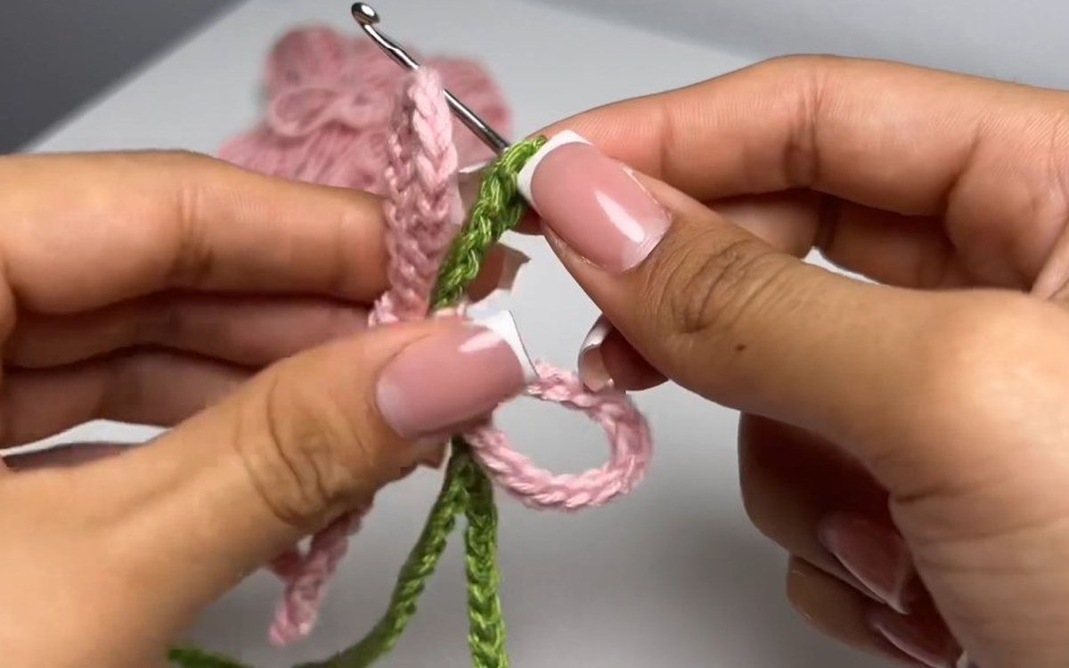 pink bow being attached to the stem of a crochet cherry keychain