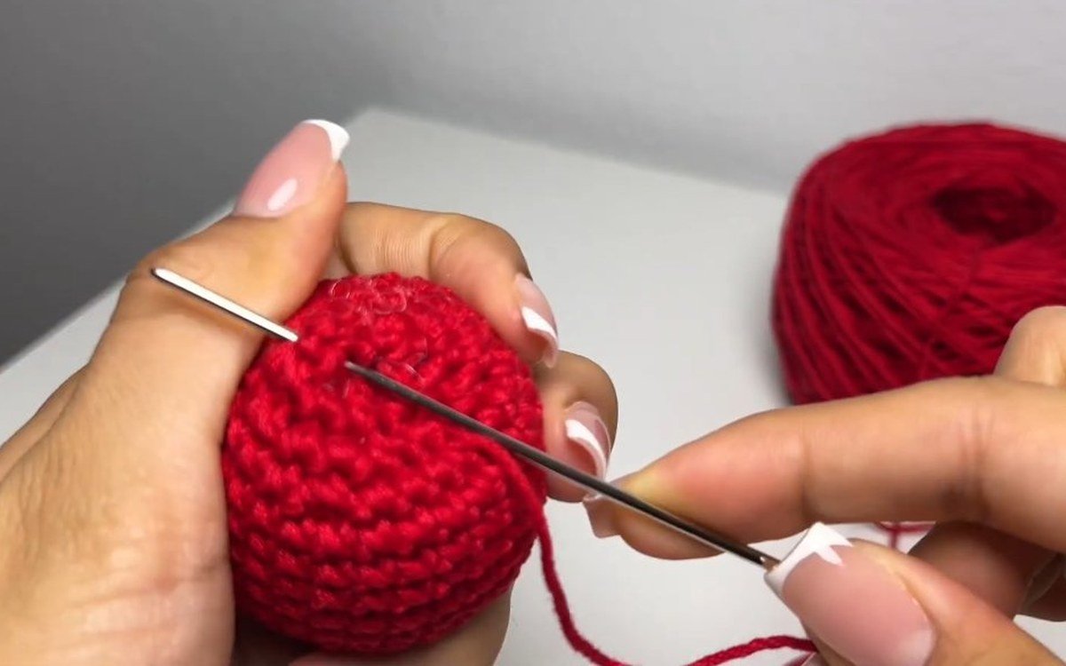 darning needle closing the top of a round crochet cherry keychain cherry