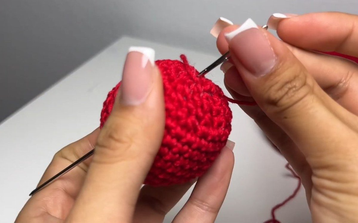 yarn tail pulled inside a finished red crochet cherry keychain cherry