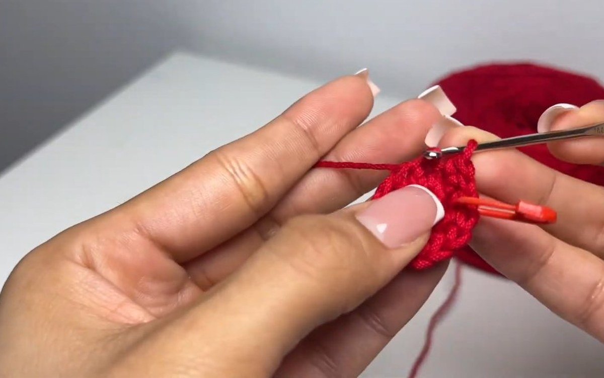 round 3 of a crochet cherry growing into a flat red disc