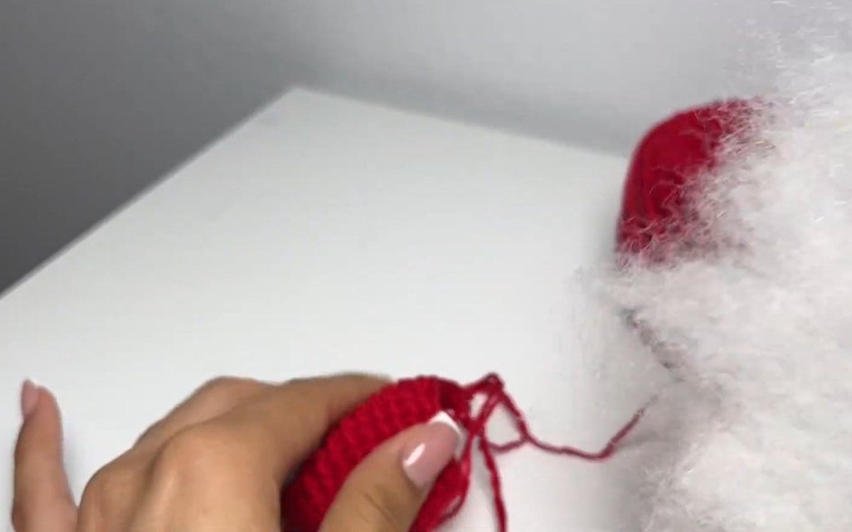 stuffing fibre fill into a red crochet cherry keychain cherry