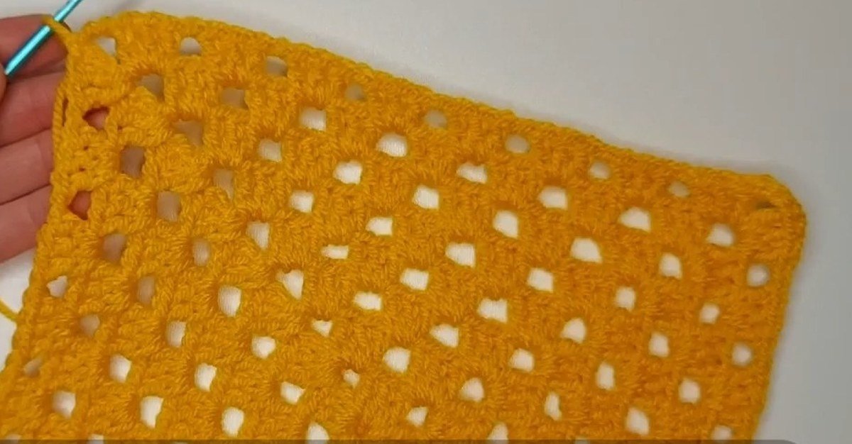 finished open granny square held up for a crochet vest pattern