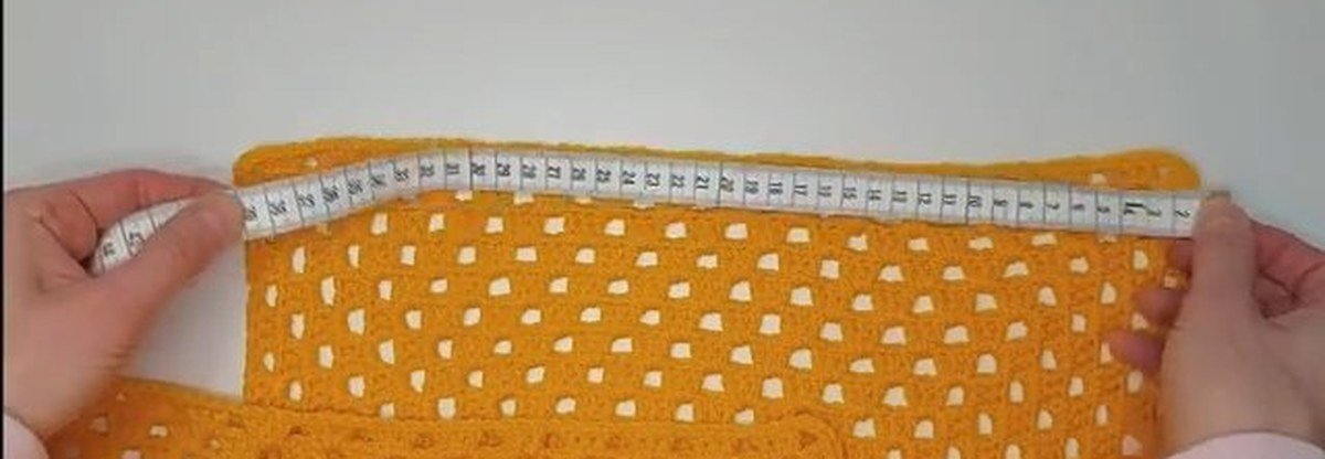 tape measure across a giant granny square for a crochet vest pattern, about 39 cm on a side