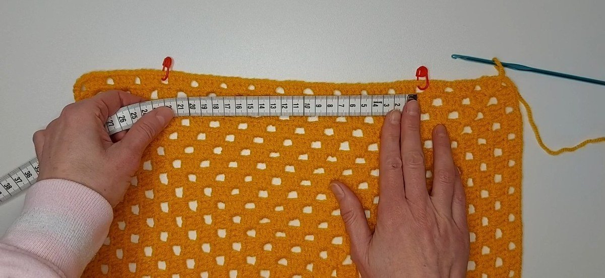 stitch markers and tape measure placing the neckline on the front panel of a crochet vest pattern
